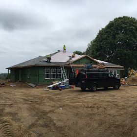 Front view of house with roof nearly complete.